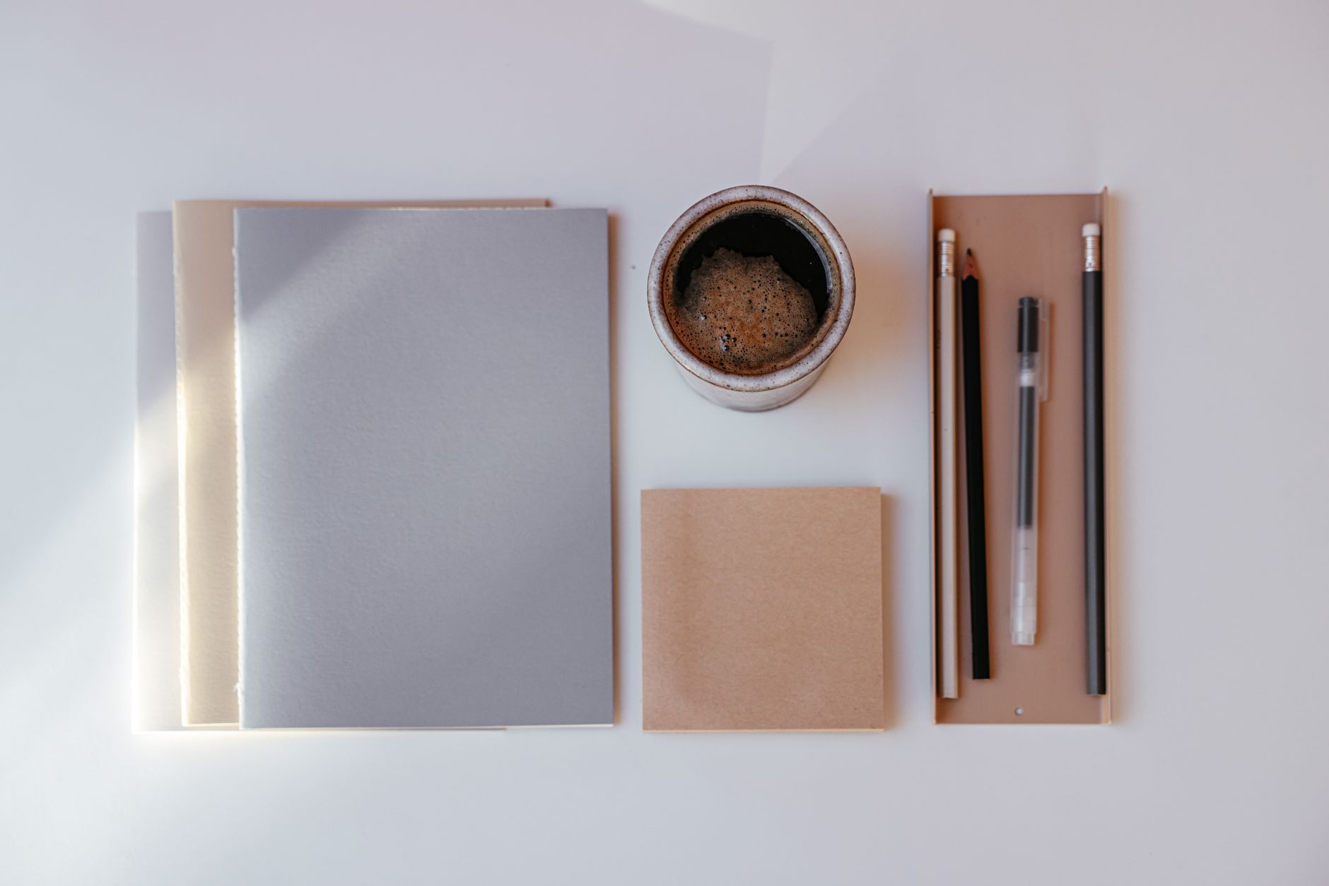 Opgeruimd bureau met notitieboekjes, een kop koffie en potloden